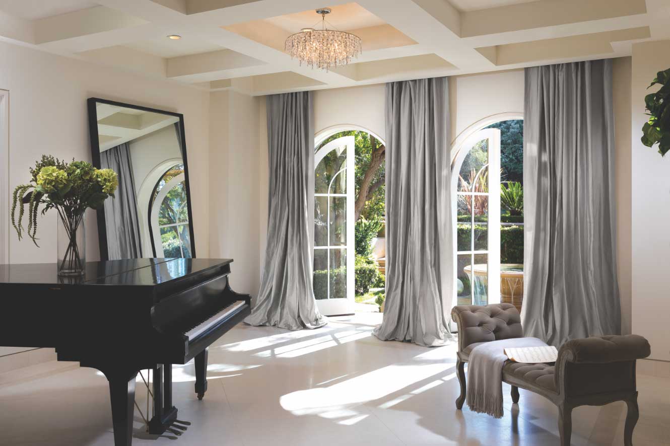 Elegant custom drapery in a Miami home featuring a piano, large mirror, chair, and big window.