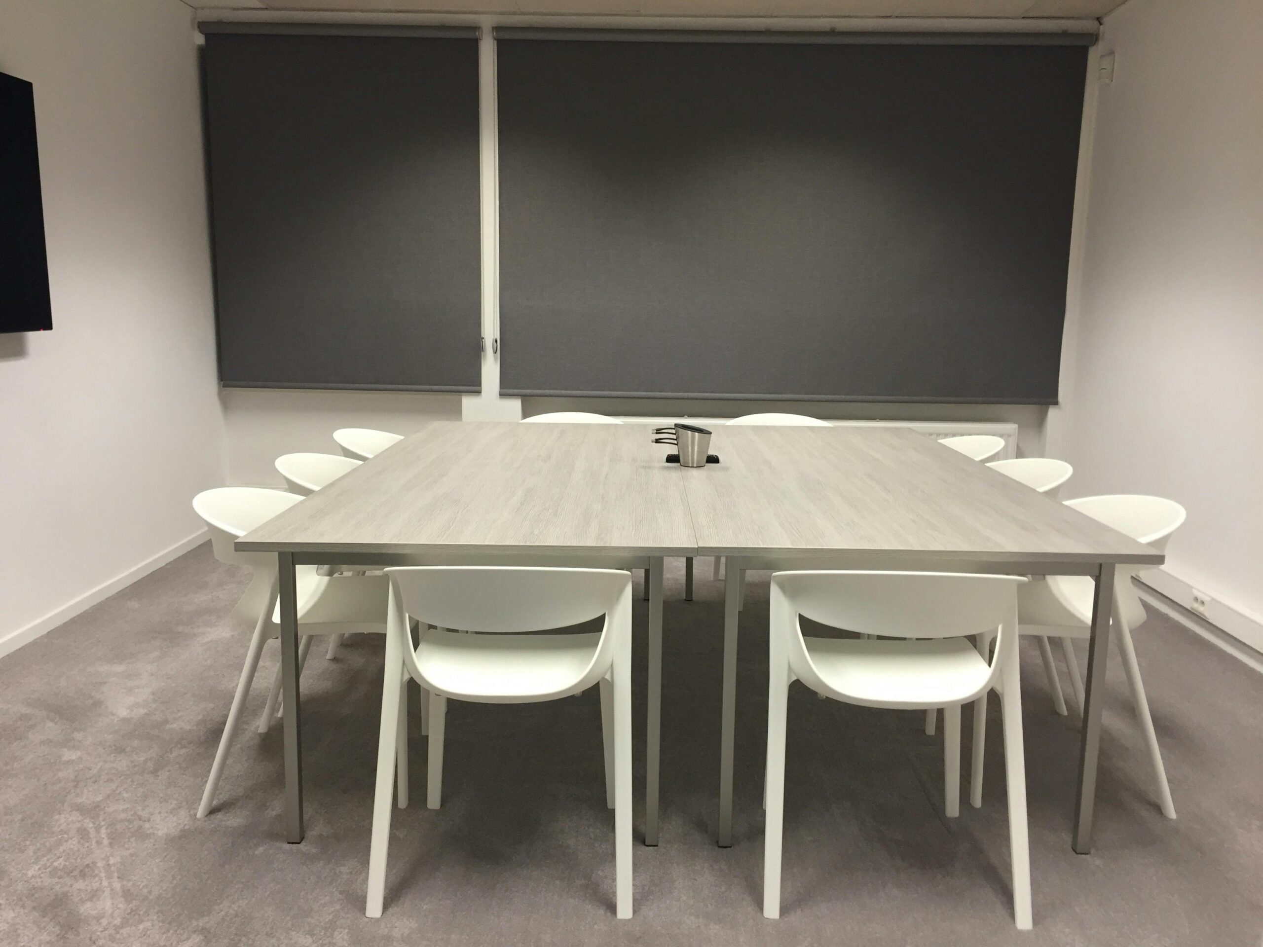 Blackout shades installed in a room with white chairs, providing complete light control and privacy.